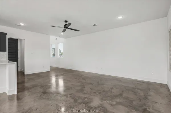 an empty room with windows and fan