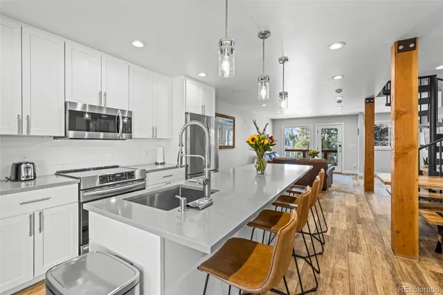 a kitchen with stainless steel appliances granite countertop a sink a stove a refrigerator cabinets and living room view