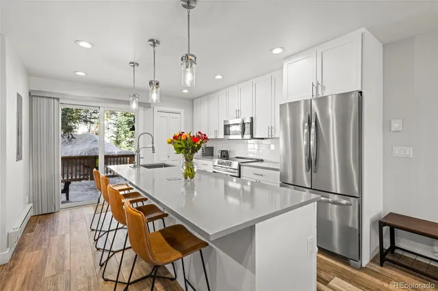 a kitchen with stainless steel appliances kitchen island granite countertop refrigerator cabinets dining table and chairs