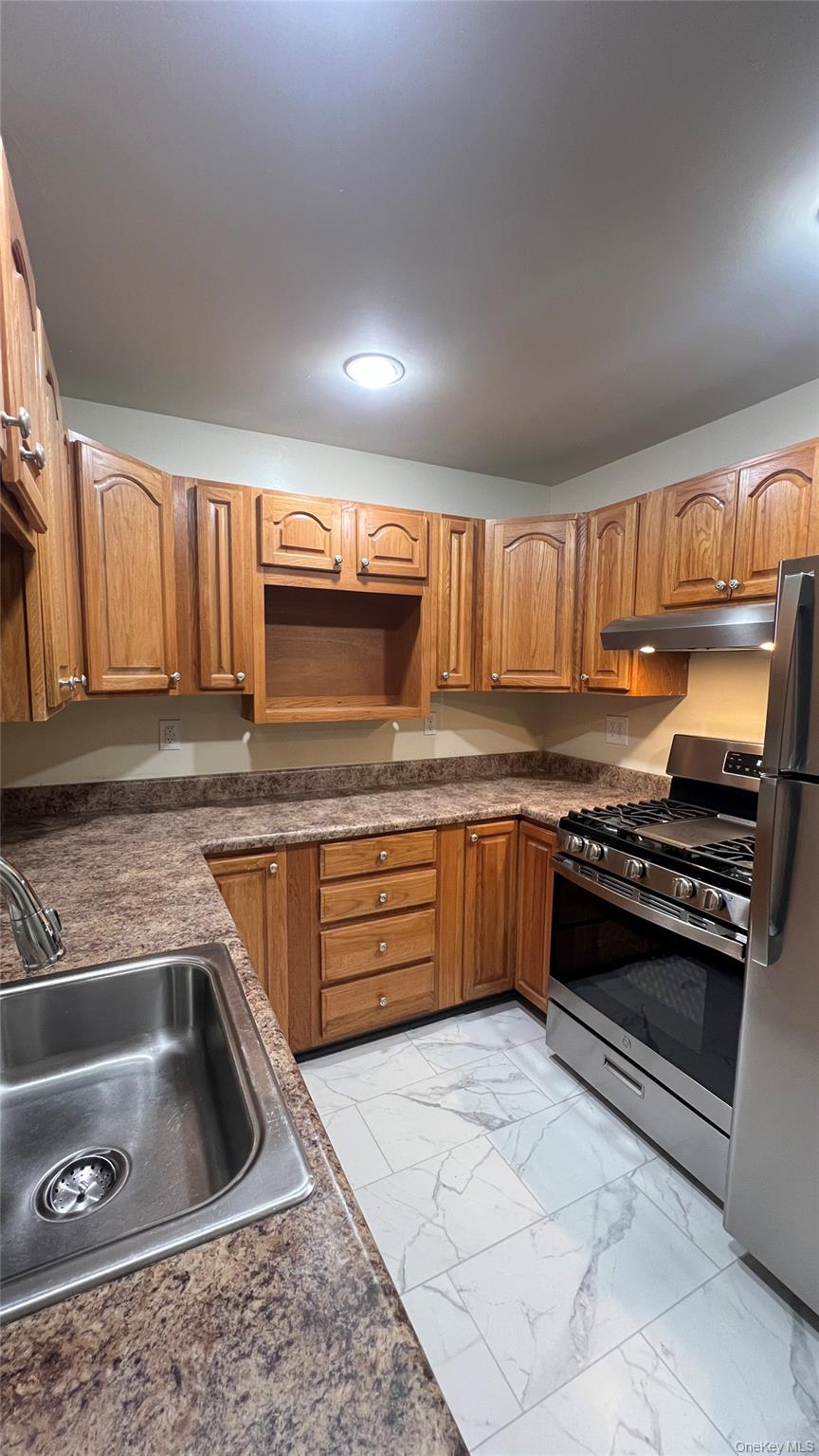 27 East Main Street, Unit 6 Beacon, NY 12508 - Photo 3 of 15 Kitchen with stainless steel appliances, brown cabinets, dark countertops, and light marble finish floors