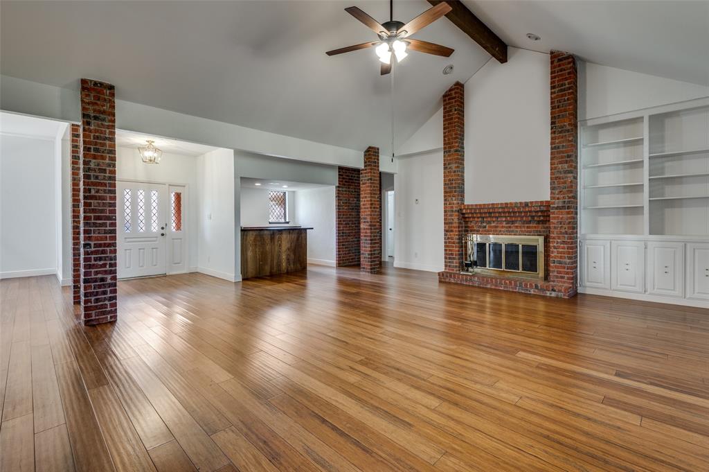 The large Living Room features a vaulted ceiling, wood center beam, brick fireplace, and a walk-in wet bar