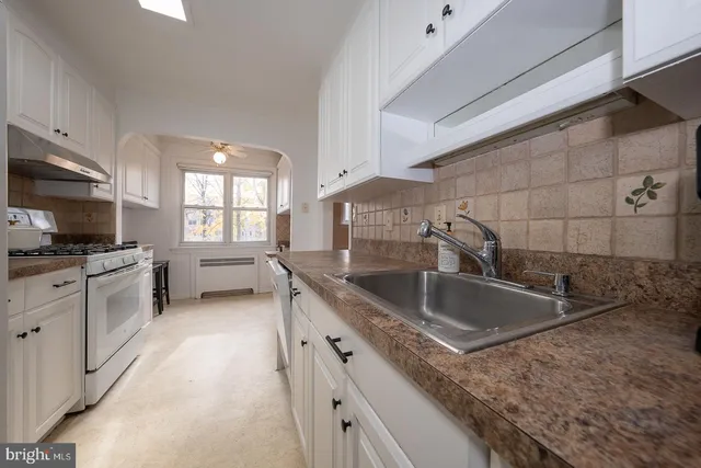 a kitchen with granite countertop a sink and a stove top oven a granite counter tops with white cabinets