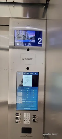 a view of an empty room with wooden floor and a kitchen