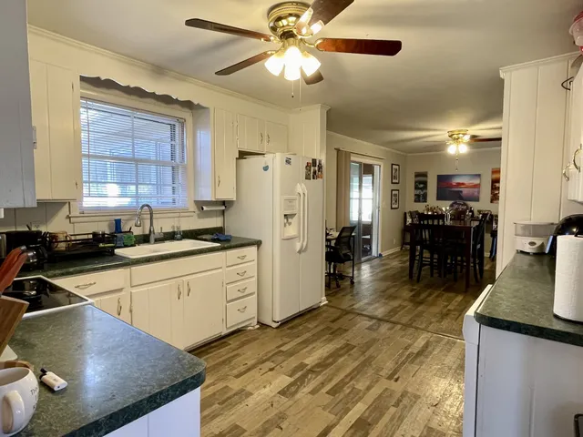 a kitchen with stainless steel appliances granite countertop a sink dishwasher and a refrigerator with wooden floor