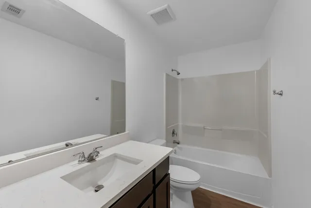 a bathroom with a bathtub shower sink vanity mirror and toilet