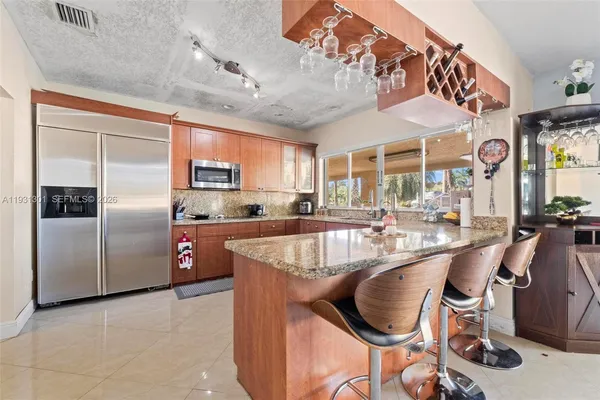 a large kitchen with stainless steel appliances kitchen island granite countertop a refrigerator and a sink