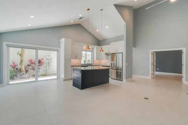 a kitchen with stainless steel appliances granite countertop a sink dishwasher and a refrigerator with wooden floor