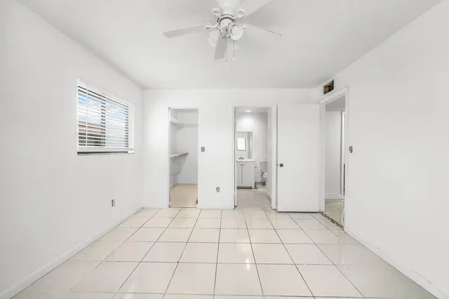 a view of an empty room with window and chandelier fan