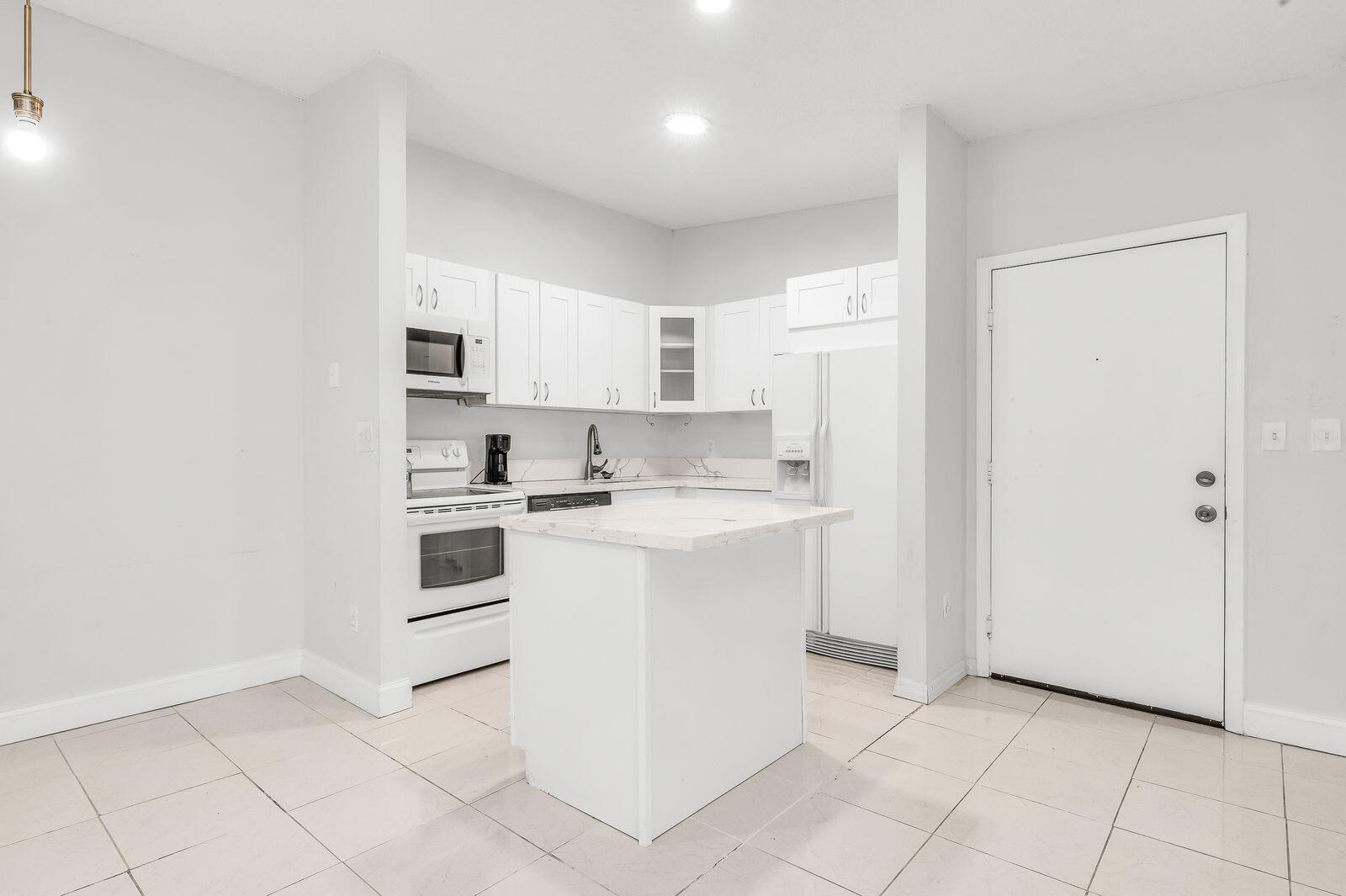 9743 West McNab Road, Unit 209 Tamarac, FL 33321 - Photo 6 of 22 a kitchen with white cabinets and white appliances
