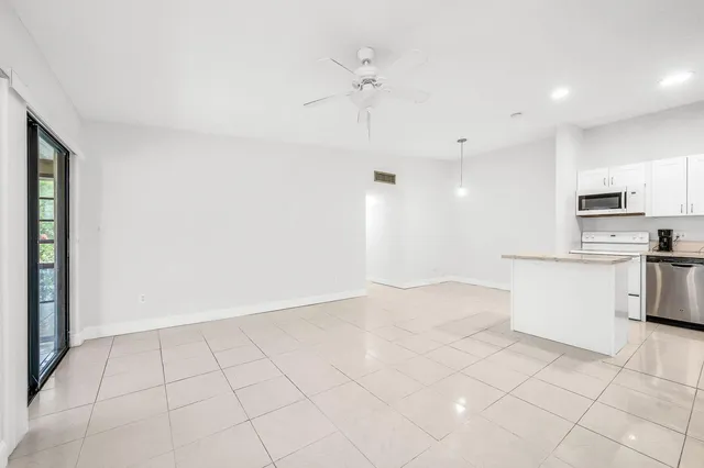 a view of a kitchen with a sink and dishwasher a refrigerator with white cabinets