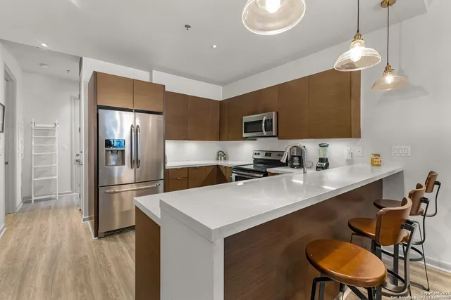 a kitchen with stainless steel appliances kitchen island a table chairs in it and wooden floors