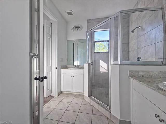 a bathroom with a granite countertop sink a mirror and a shower