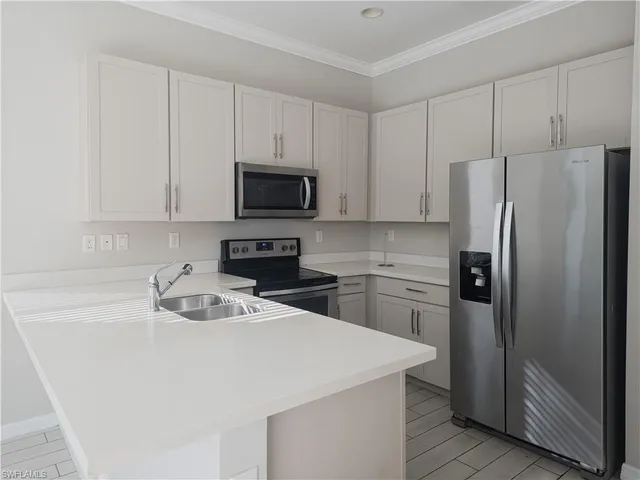 a kitchen with refrigerator a microwave a sink and cabinets