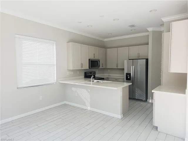 a kitchen with stainless steel appliances granite countertop a refrigerator a sink dishwasher a stove top oven a refrigerator and white cabinets with wooden floor