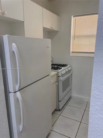 a white refrigerator freezer and a stove sitting inside of a kitchen