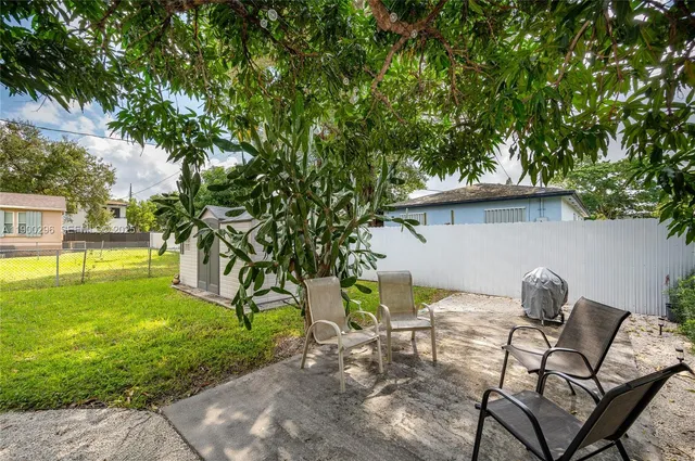 a view of a backyard with table and chairs potted plants and wooden fence