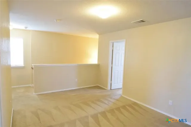 a view of an empty room with a chandelier fan