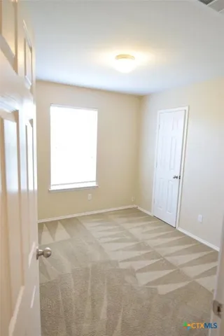 an empty room with chandelier fan and windows