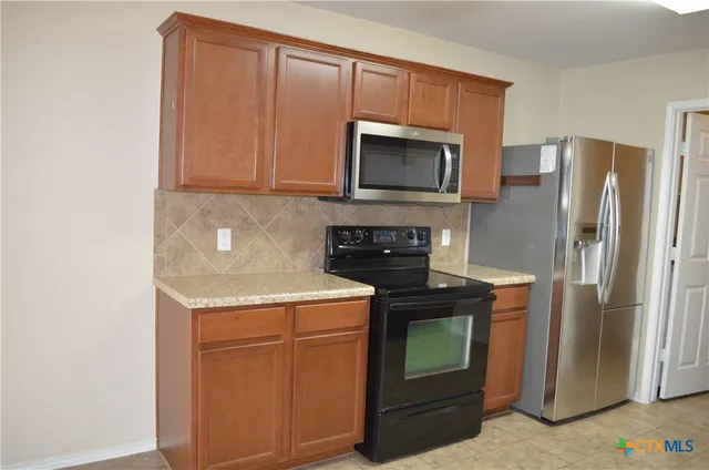 a large kitchen with granite countertop a stove a sink and a refrigerator