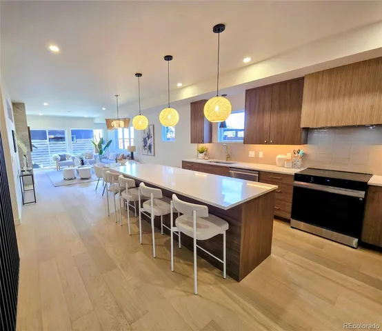 a kitchen with stainless steel appliances granite countertop a stove a sink a oven a dining table and chairs with wooden floor