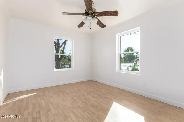 an empty room with windows and fan