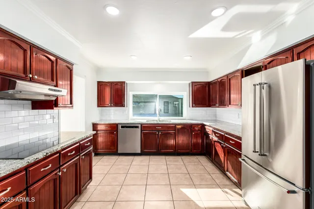 a kitchen with stainless steel appliances granite countertop a sink and dishwasher a refrigerator with wooden cabinets