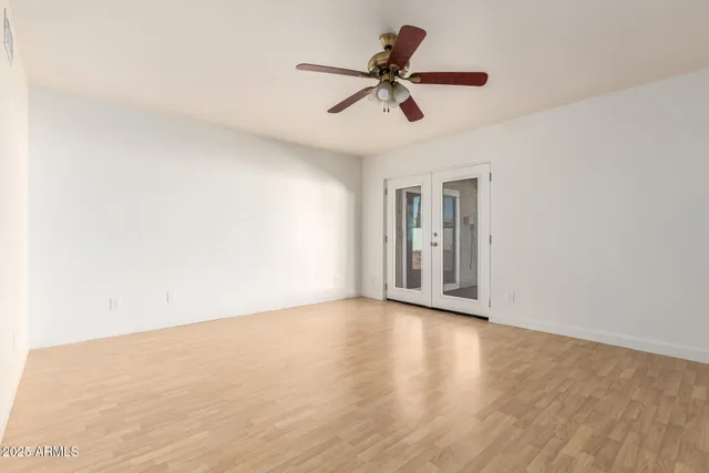 a view of empty room with wooden floor and ceiling fan