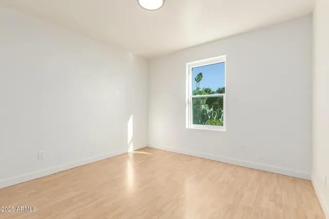 an empty room with wooden floor and window