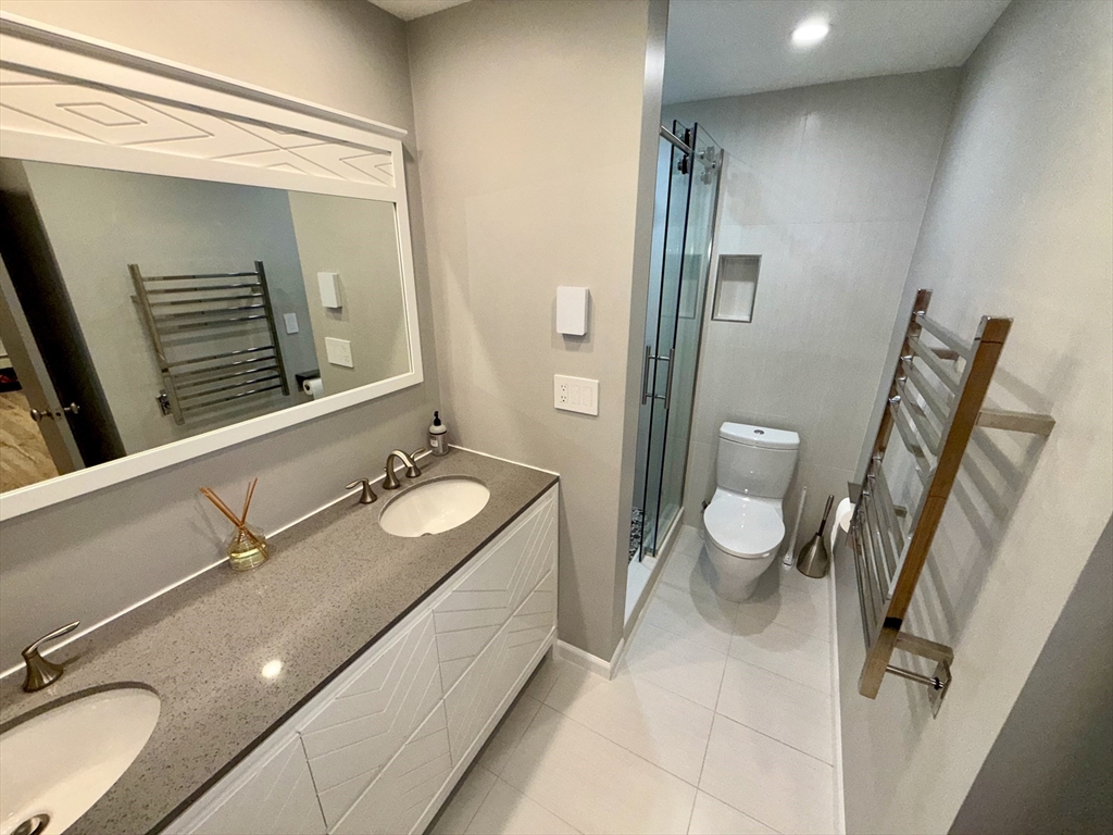 1206 Greendale Avenue, Unit 201 Needham, MA 02492 - Photo 25 of 39 a bathroom with a granite countertop double vanity sink a mirror and a toilet