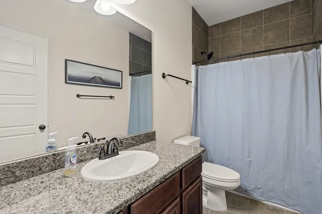 a bathroom with a granite countertop sink toilet and a mirror