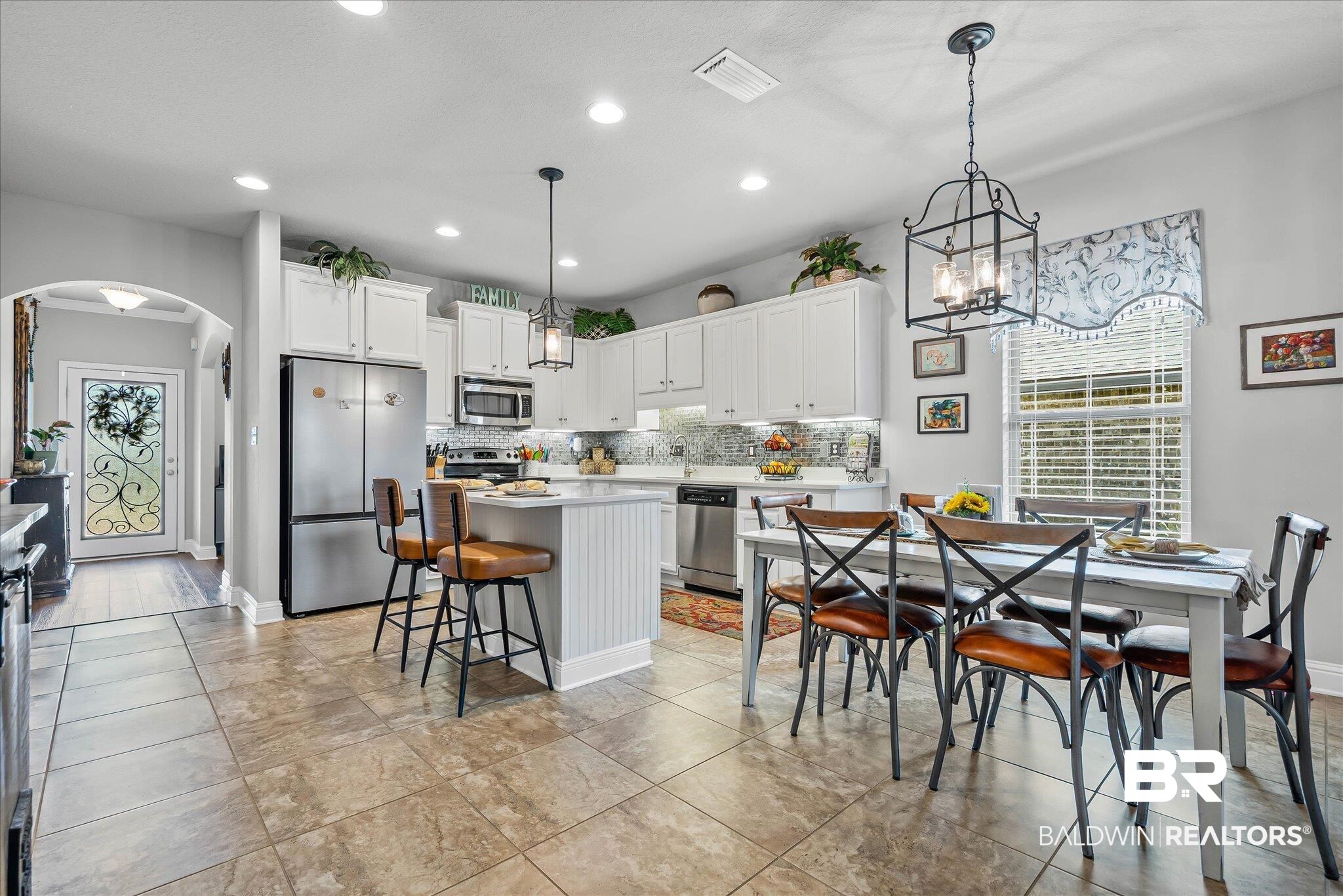 10677 Orkney Way Spanish Fort, AL 36527 - Photo 5 of 22 Kitchen featuring appliances with stainless steel finishes, white cabinets, arched walkways, a center island, and hanging light fixtures