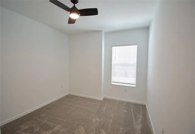 an empty room with a window and a fan