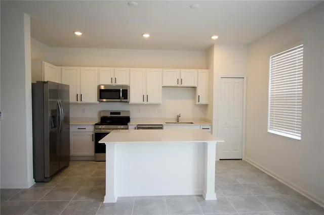 a kitchen with a refrigerator a stove top oven and white cabinets
