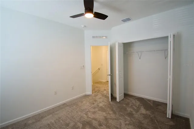 an empty room with a ceiling fan and carpet