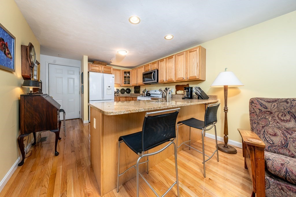 17 North Ridge Road, Unit 444 Mashpee, MA 02649 - Photo 3 of 18 a kitchen with stainless steel appliances granite countertop a stove a refrigerator a sink a dining table and chairs with wooden floor
