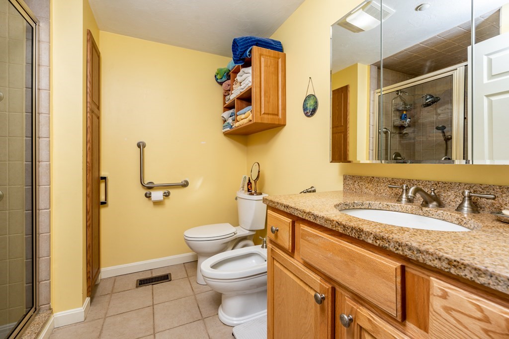 17 North Ridge Road, Unit 444 Mashpee, MA 02649 - Photo 9 of 18 a bathroom with a granite countertop toilet sink and mirror