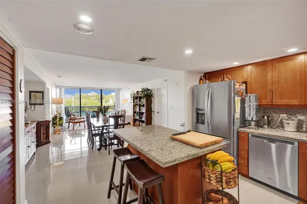 a kitchen with stainless steel appliances granite countertop sink stove refrigerator dining table and chairs