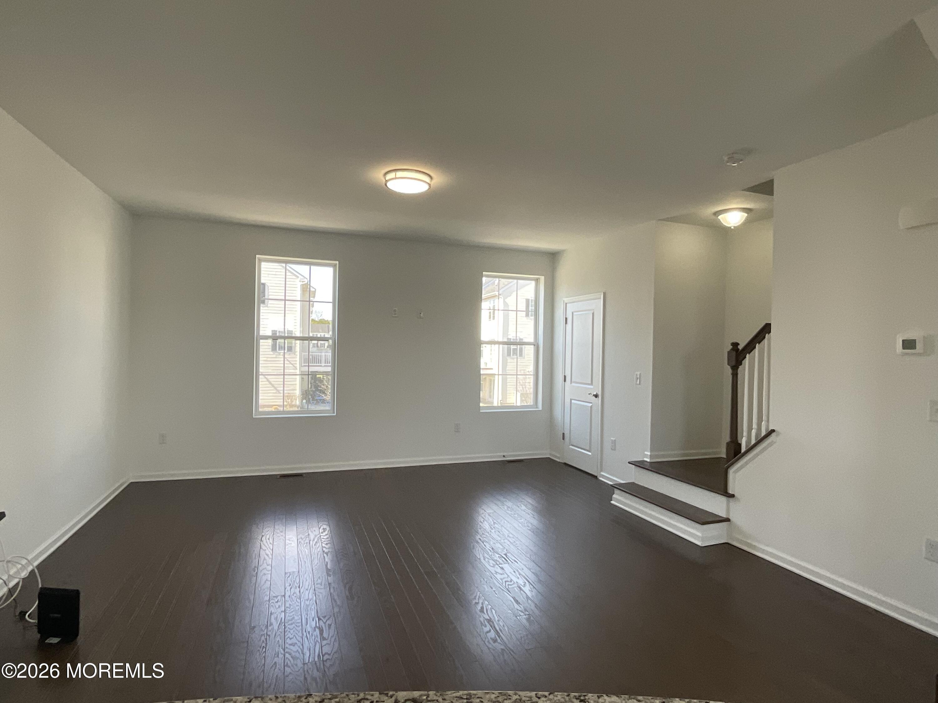 304 Prestige Road, Unit 2404 Brick, NJ 08723 - Photo 6 of 25 an empty room with wooden floor and windows with curtains