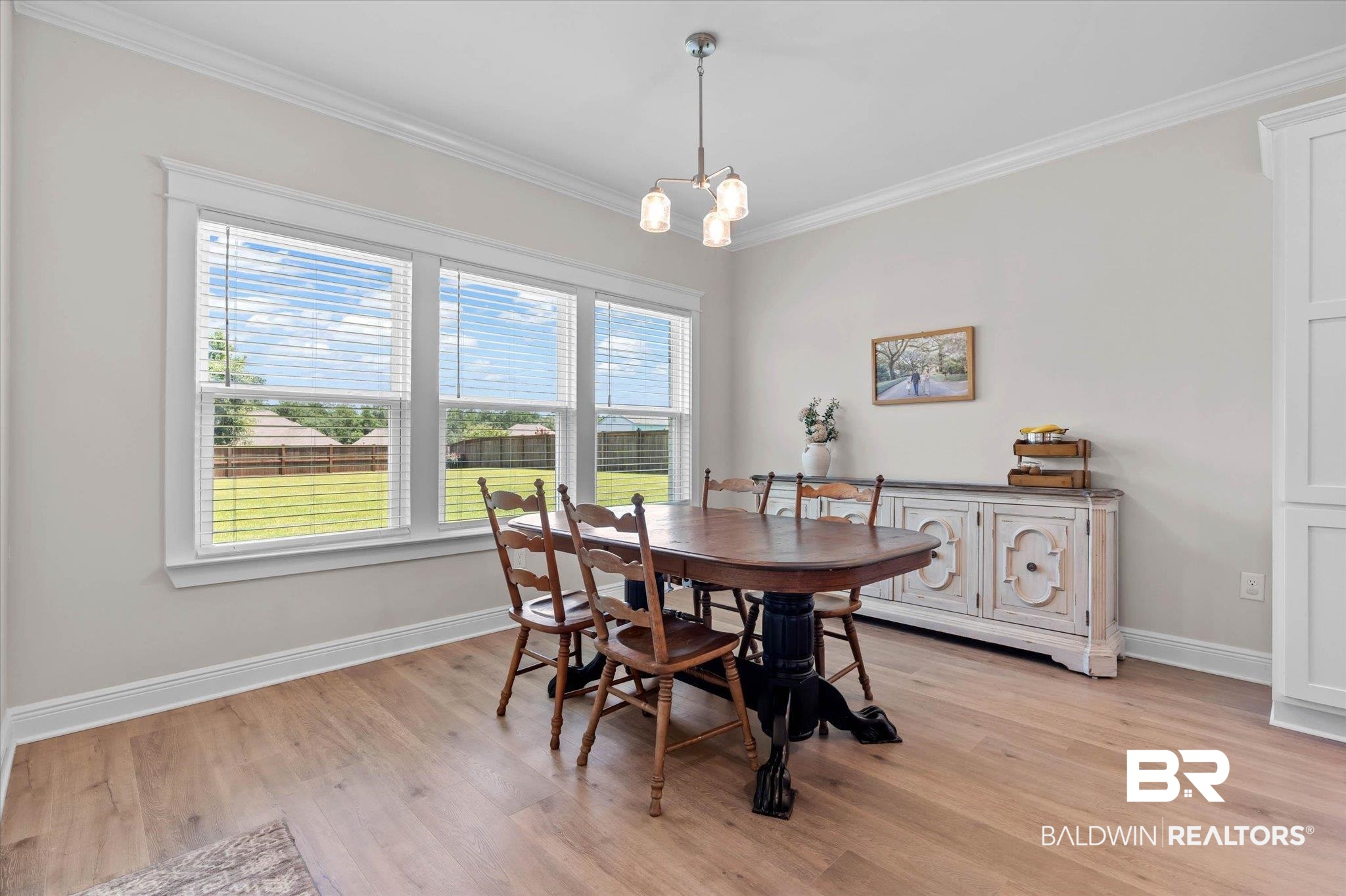 23523 Travis Stock Street Foley, AL 36535 - Photo 13 of 45 Dining area featuring wood-finish flooring, a three-panel window with white blinds, and crown molding