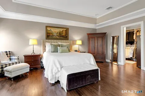 a spacious bedroom with a bed a dresser and wooden floor