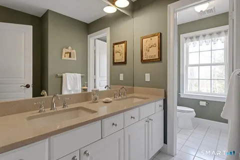 a bathroom with a granite countertop double vanity sink a mirror and a bathtub