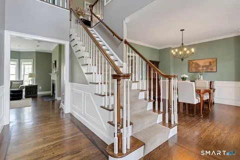 a view of a hallway with wooden floor stairs and a chandelier