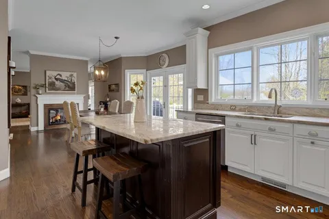 a kitchen with granite countertop a stove a sink a dining table and chairs with wooden floor