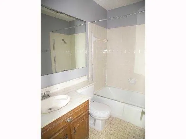 a bathroom with a granite countertop bathtub shower sink mirror and toilet