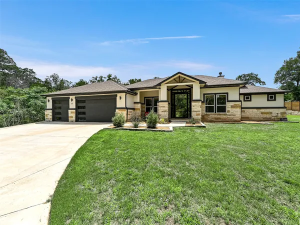 a front view of a house with a yard and trees