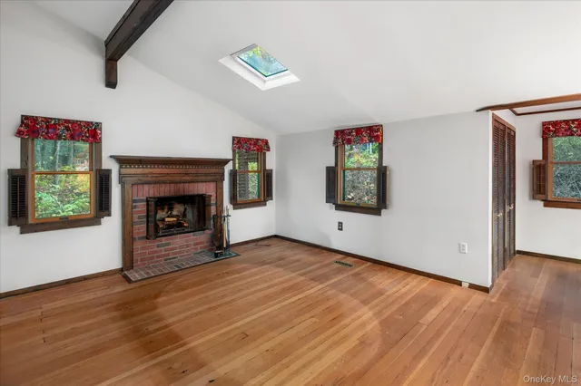 an empty room with windows fireplace and wooden floor
