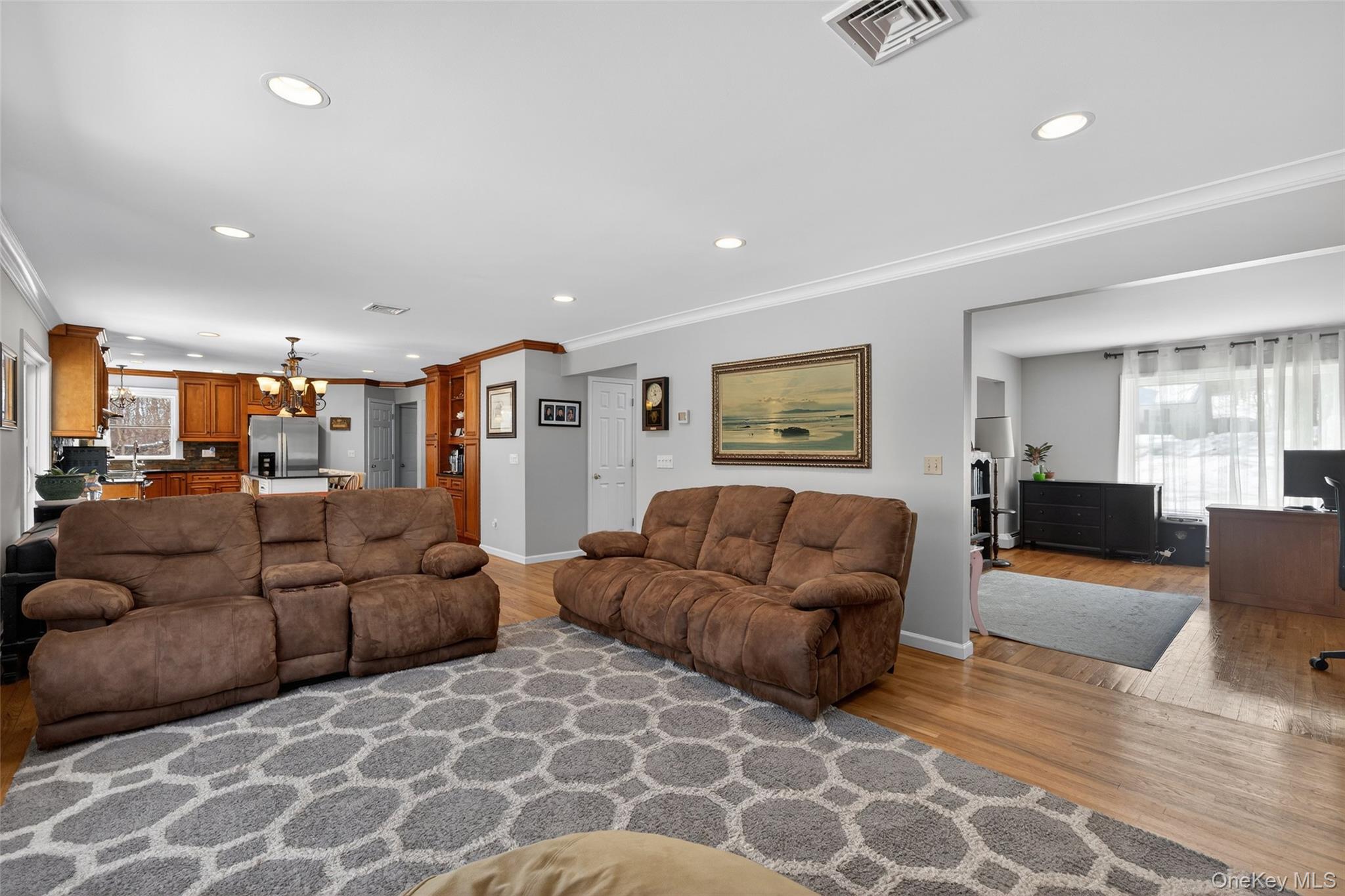 34 Booth Road Chester, NY 10918 - Photo 14 of 42 Family room featuring wood-style flooring, crown molding, hanging lights, and view into an office area