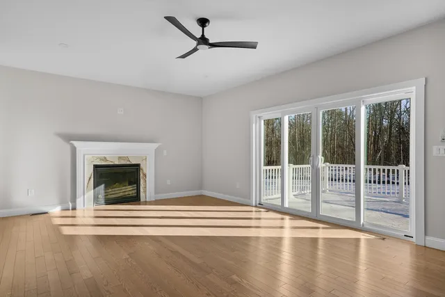 a view of an empty room with wooden floor and a fireplace