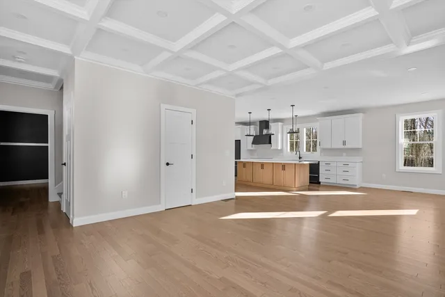 an empty room with wooden floor and kitchen