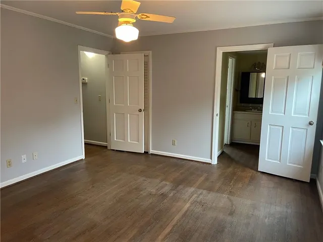 an empty room with closet and a ceiling fan